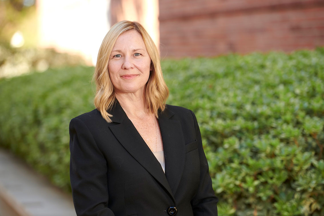 Portrait of Amander Clark with shurbs and building in the background