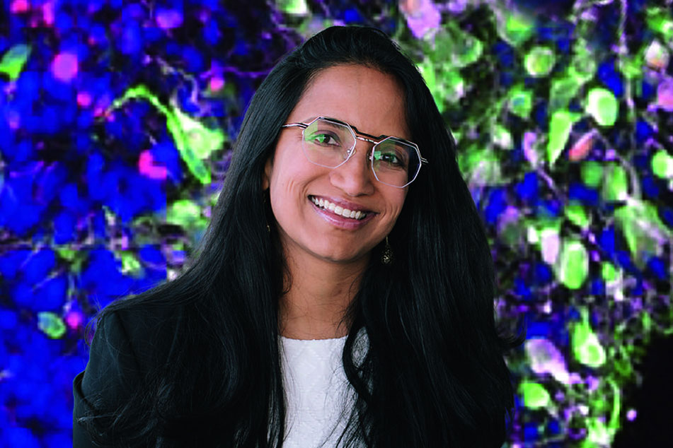 Assistant professor Aparna Bhaduri smiles in front of ivy plants